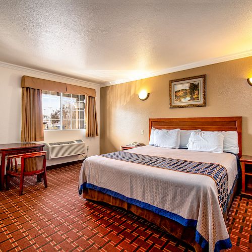 A clean and tidy hotel room features a double bed, two nightstands, a table with chairs, and a window with a pleasant view, ending the sentence.