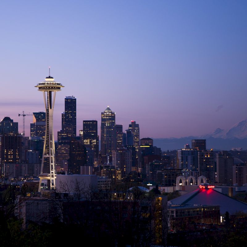 This image features the Seattle skyline at dusk, highlighting the Space Needle with Mount Rainier in the background.
